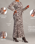 A woman modeling a long-sleeve maxi dress with a zebra-inspired print, shown against a light gray studio background with callout circles and text highlighting features like hidden side pockets, sleeve slits, tie waist belt, and side slits.