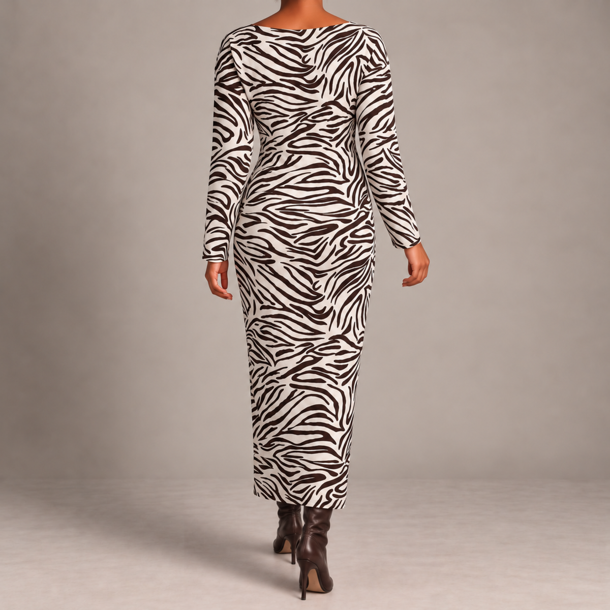 A woman modeling a long-sleeve, bodycon maxi dress with a dark brown and white zebra print, paired with dark brown heeled boots, shot from behind against a neutral gray studio background.