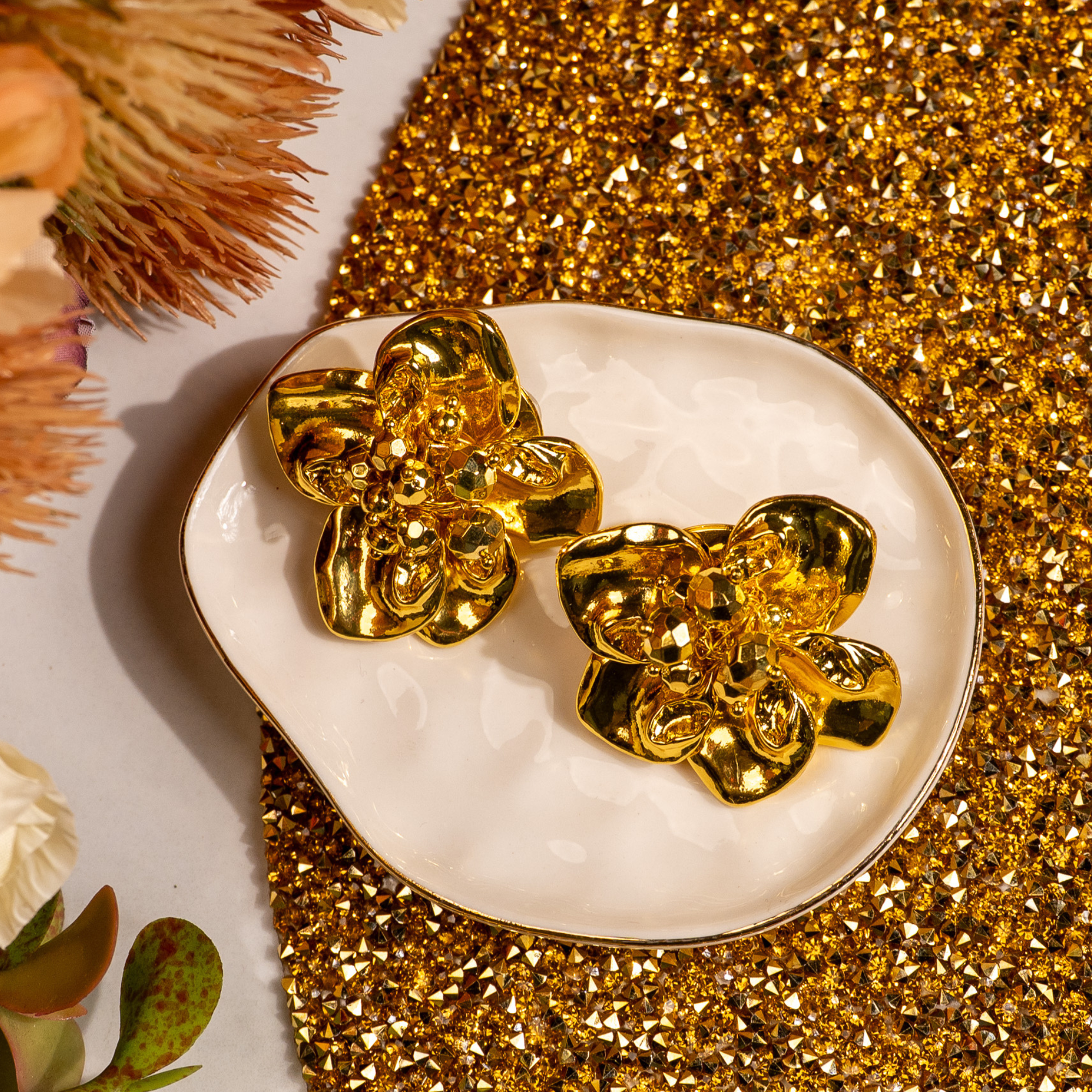 18k gold sculptural floral statement earrings inspired by wisteria blossoms with layered petals and faceted gold center worn on a woman’s ear