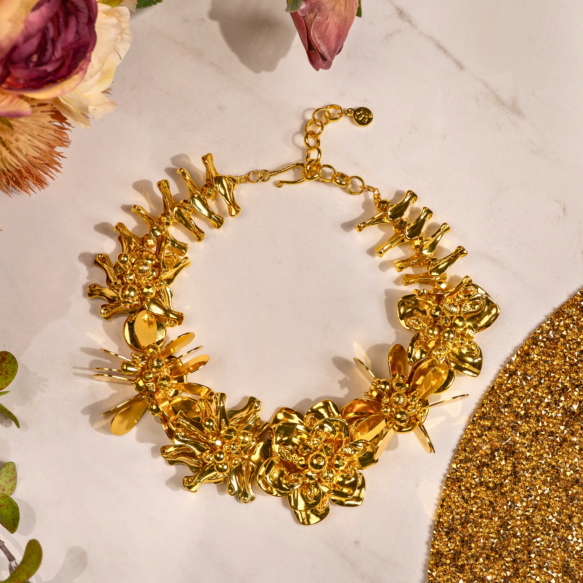 18k gold sculptural floral statement necklace with layered petals and reflective discs inspired by cascading wisteria blossoms worn on a woman's neckline