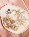 Mother of pearl floral statement bracelet with pearl cluster centers inspired by wisteria blossoms worn on a woman's wrist