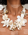 Mother of pearl floral statement necklace with sculptural petals and pearl clusters inspired by wisteria blossoms worn on a woman's neckline