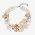 Mother of pearl floral statement necklace with sculptural petals and pearl clusters inspired by wisteria blossoms worn on a woman's neckline