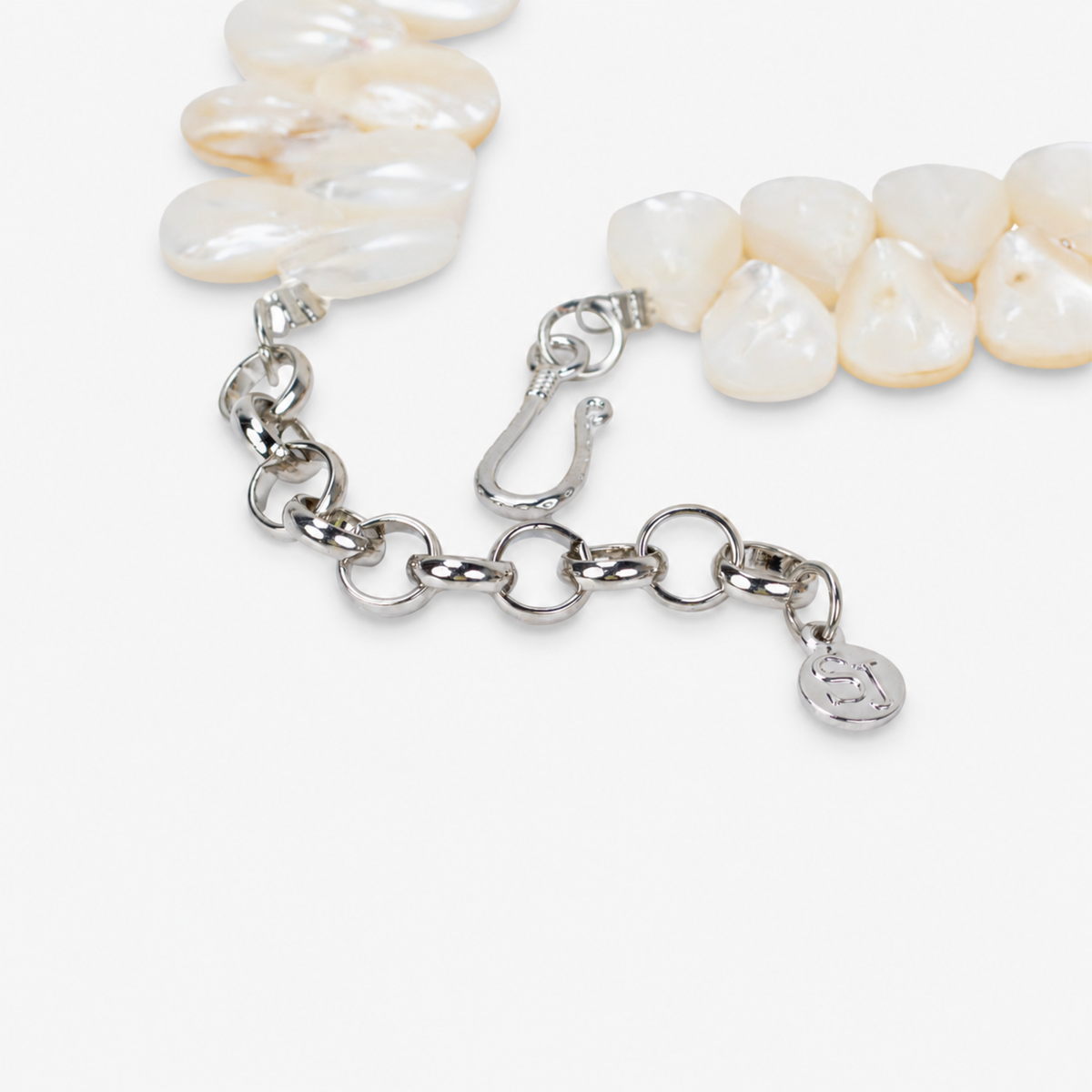 Mother of pearl floral statement necklace with sculptural petals and pearl clusters inspired by wisteria blossoms worn on a woman's neckline