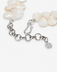 Mother of pearl floral statement necklace with sculptural petals and pearl clusters inspired by wisteria blossoms worn on a woman's neckline