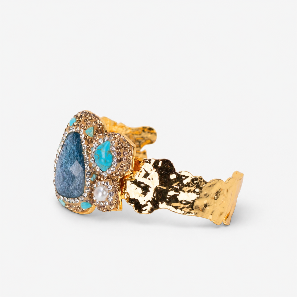Blue statement cuff featuring an organic arrangement of blue green stones, creamy accents and Gold tone finish detailing.