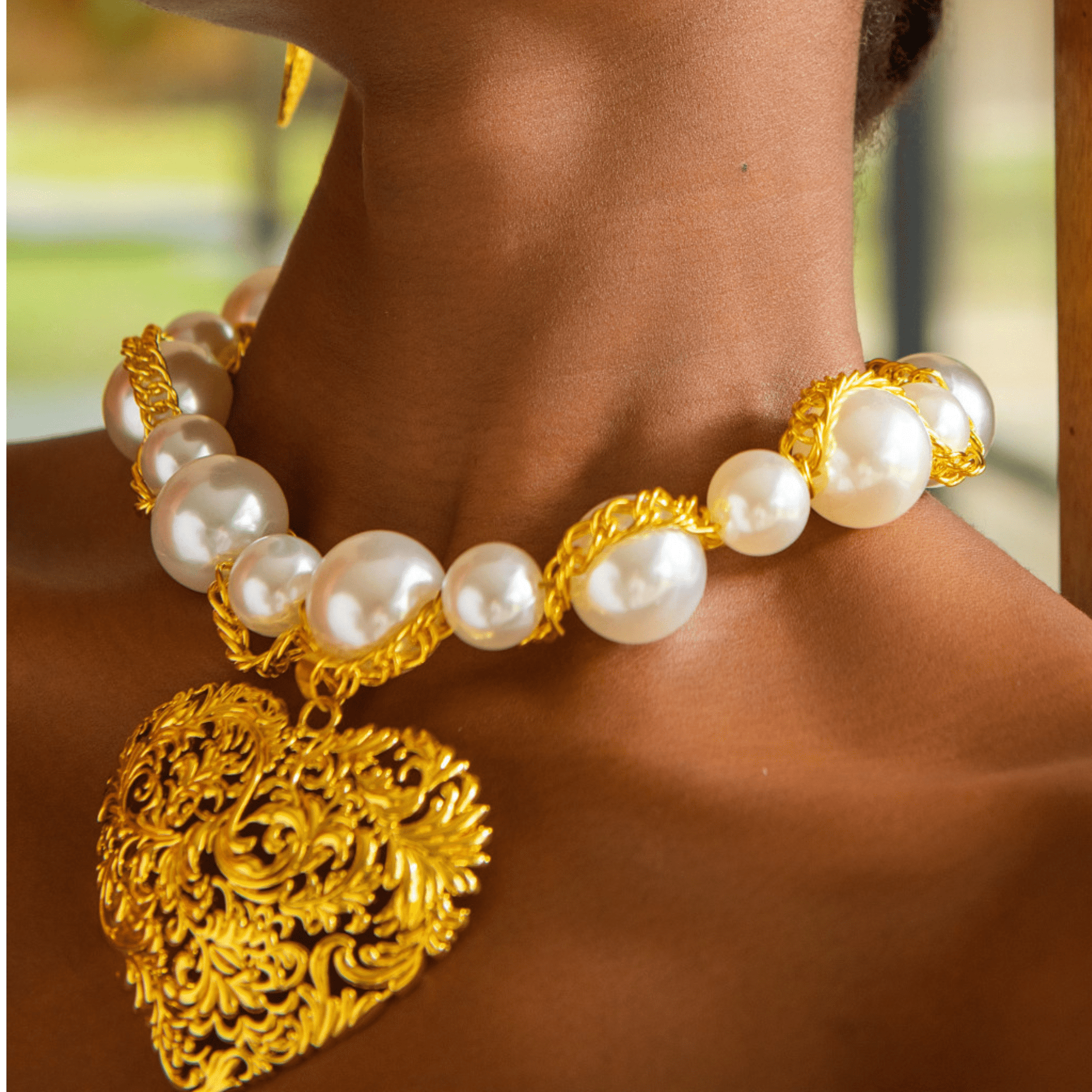 Close-up of Amora gold and pearl statement necklace on neckline.