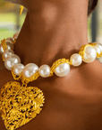 Close-up of Amora gold and pearl statement necklace on neckline.