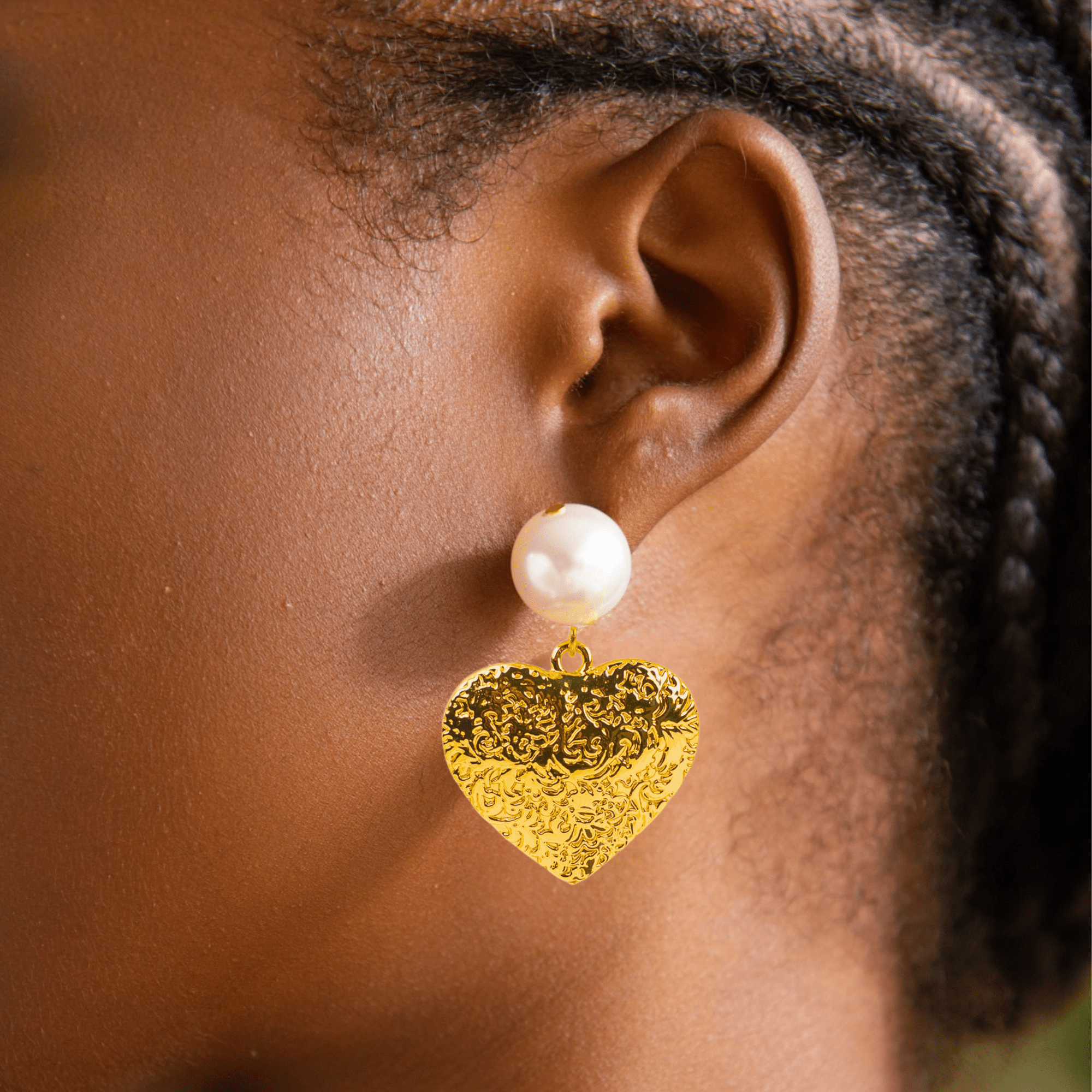 Close-up of Amora Pearl Heart Dangle on ear, gold and ivory details.