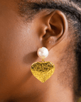 Close-up of Amora Pearl Heart Dangle on ear, gold and ivory details.