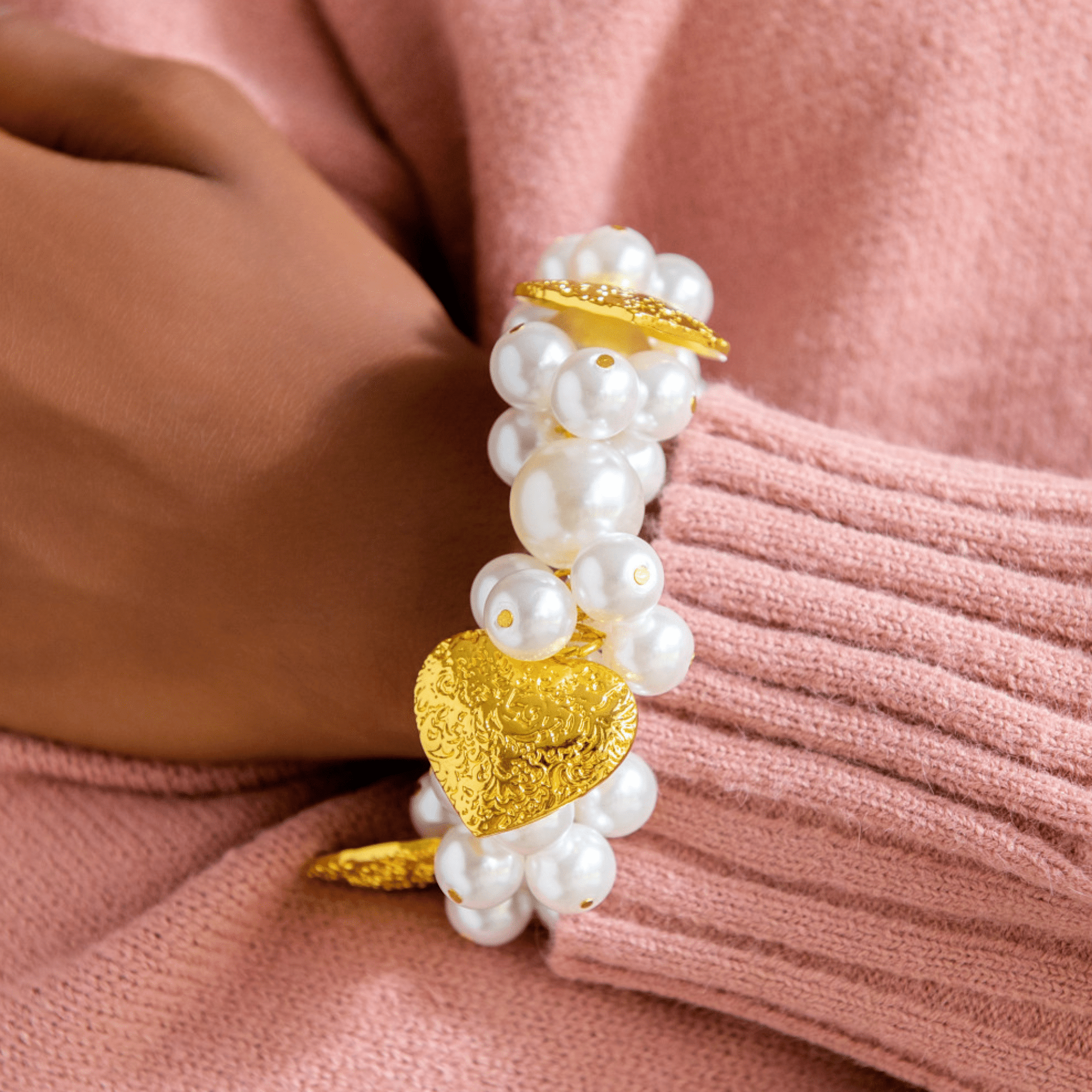 Model wearing Amora Pearl Heart Stretch Bracelet styled with pink sweater.