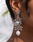 Paloma silver angelfish dangle earrings featuring sculpted fish, dimensional coral inspired detailing and luminous pearl drops.
