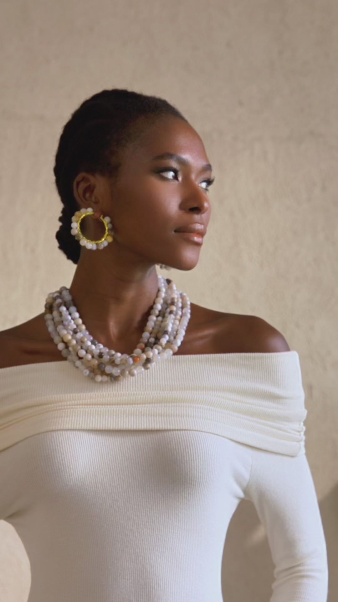 Gold hoop earrings with natural Botswana agate beads in ivory and neutral tones wrapped around a circular hoop design.
