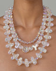 Close up of layered iridescent statement necklace with clustered bubble beads and a delicate faceted center strand.
