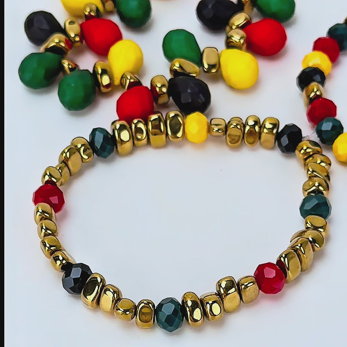 Three piece statement bracelet stack featuring red, green, yellow and black teardrop and round beads.