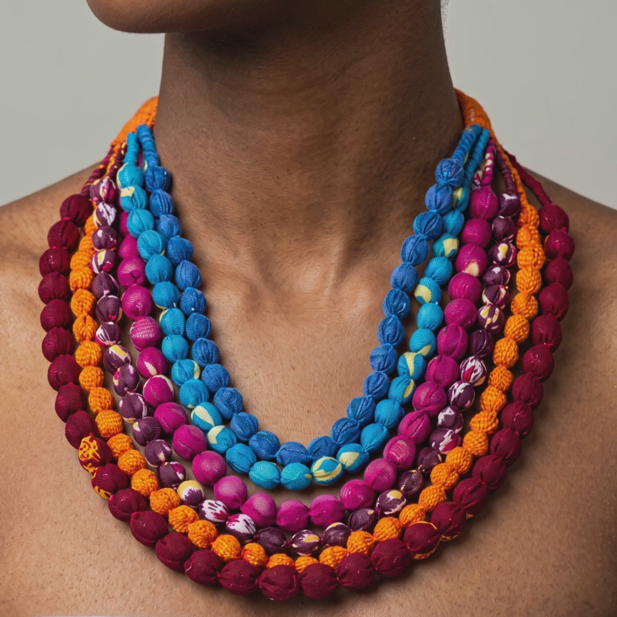Close view of Kenza Cloth Bead Bib featuring saturated multicolor beads in mixed solid and patterned fabrics.
