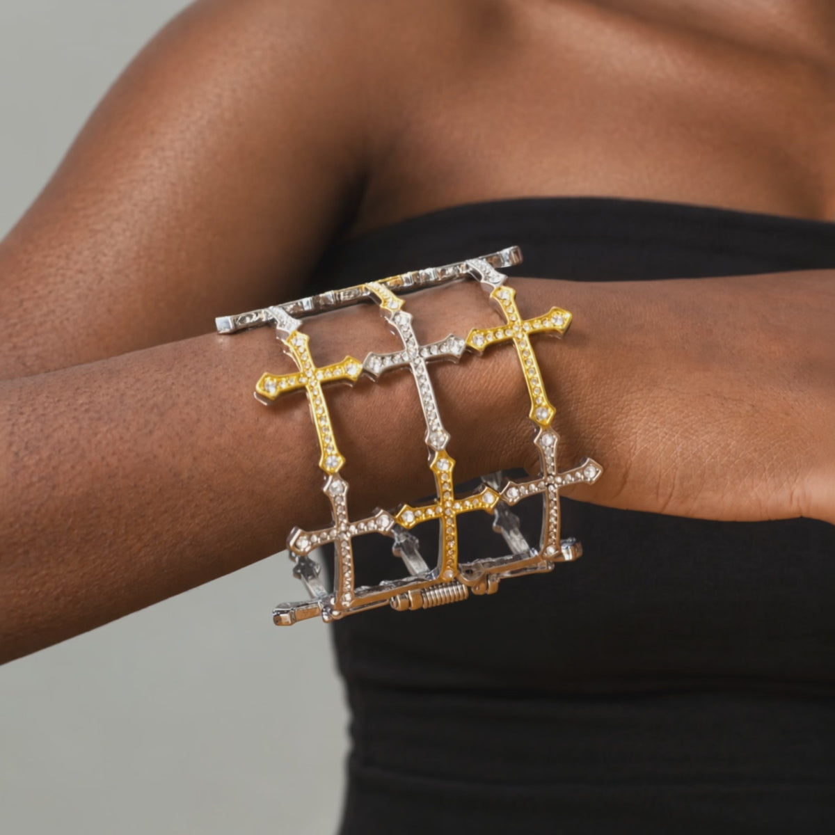 Close up of mixed metal statement cuff featuring gold cross accents surrounded by silver cross motifs.   Trinity statement bracelet featuring an openwork cross design with
