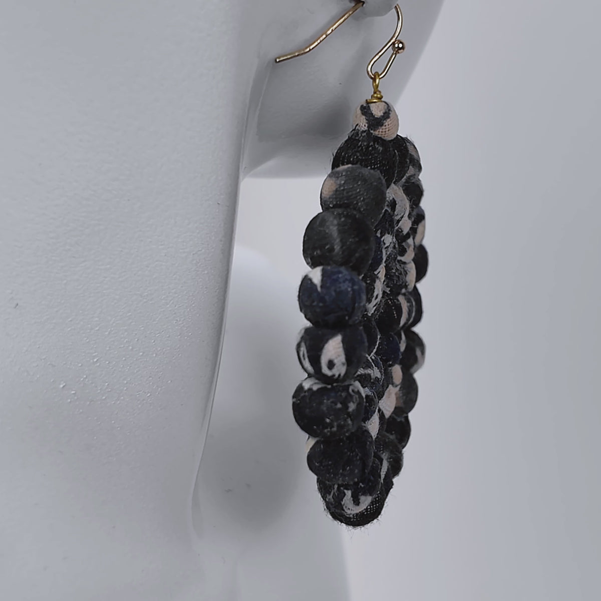 Black and white fabric bead earrings with an open circular silhouette and gold colored hooks.