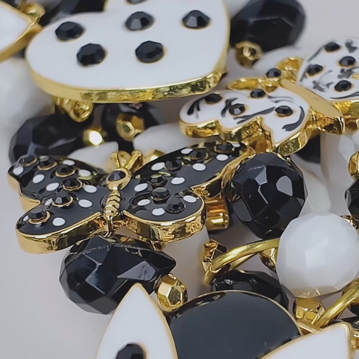 Close up of Sassy Jones Lovebug Brooch Bib with faceted black beads, white beads and removable decorative charms.