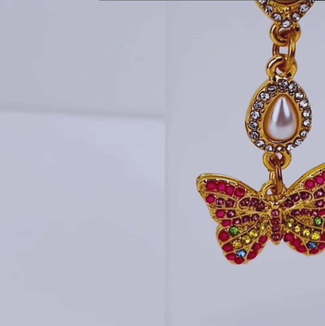 Crystal butterfly dangle earrings featuring multicolored pavé crystals, pear shaped crystal accents, and gold tone detailing.