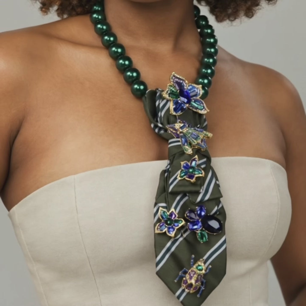 Close up of Valerie Miss Beasley necktie showcasing blue and green crystal flowers with ornate insect inspired brooches. 