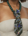 Close up of Valerie Miss Beasley necktie showcasing blue and green crystal flowers with ornate insect inspired brooches. 