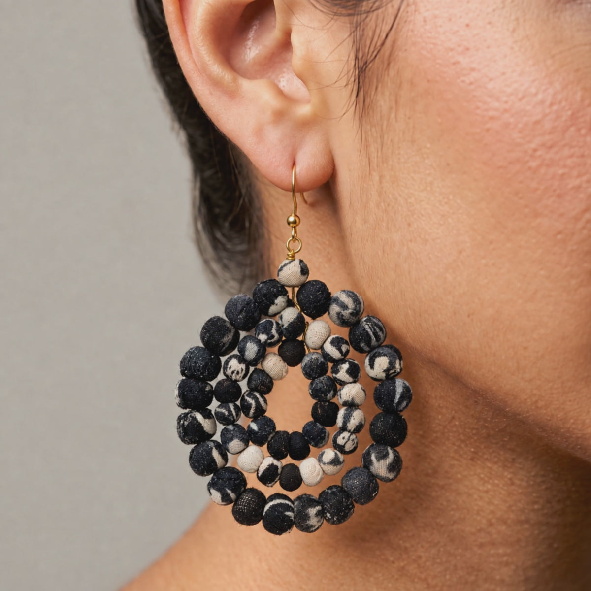 Black and white fabric bead earrings with an open circular silhouette and gold colored hooks.
