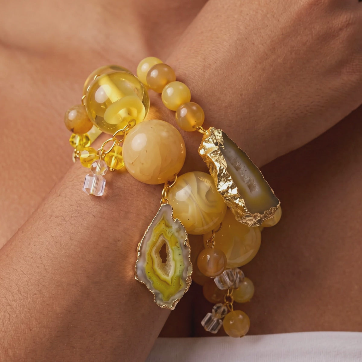 Chunky yellow bracelet stack featuring natural stone variations, citrus colored beads, and decorative hanging accents.