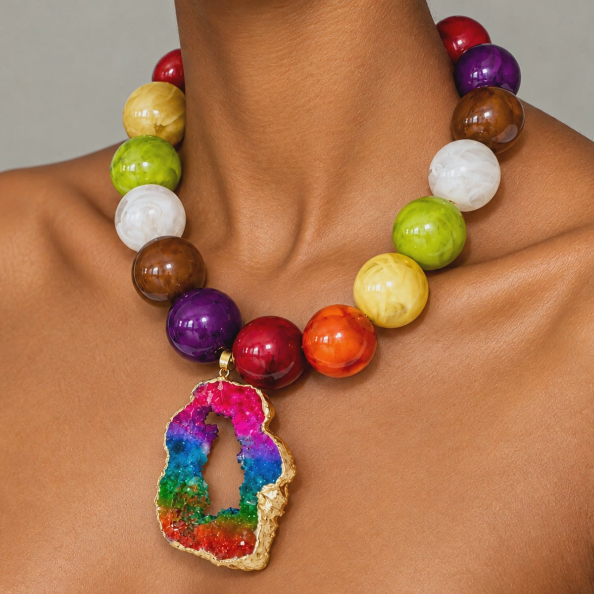 Rainbow statement jewelry featuring a raw sliced agate pendant and vibrant jewel toned beads.