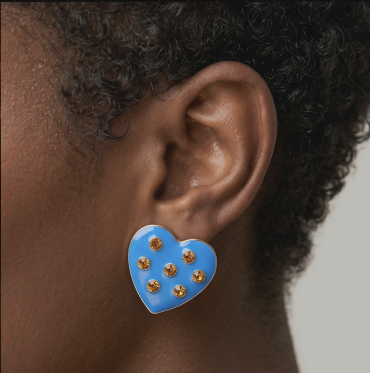 Blue heart stud earrings featuring a glossy finish, warm golden crystals and polished gold detailing.