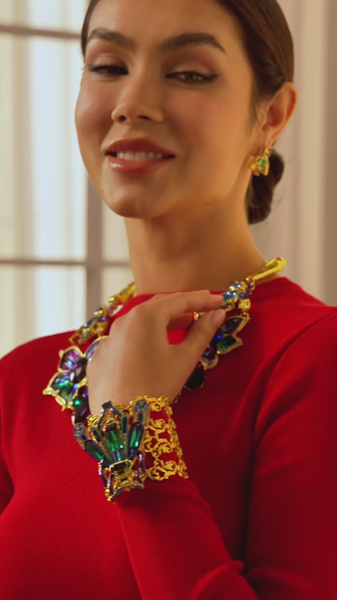 Gold cuff bracelet with amethyst, blue, and green crystals featuring a detailed beetle design and sculptural gold framework.