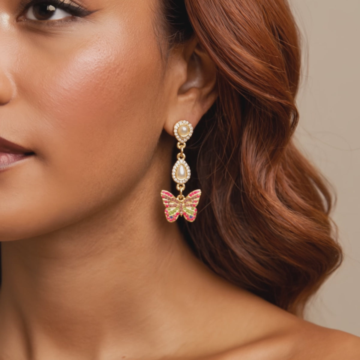 Crystal butterfly dangle earrings featuring multicolored pavé crystals, pear shaped crystal accents, and gold tone detailing.