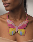 Statement butterfly bib necklace featuring vibrant multicolored crystals in coral, pink, gold, turquoise, and emerald with gold tone detailing.