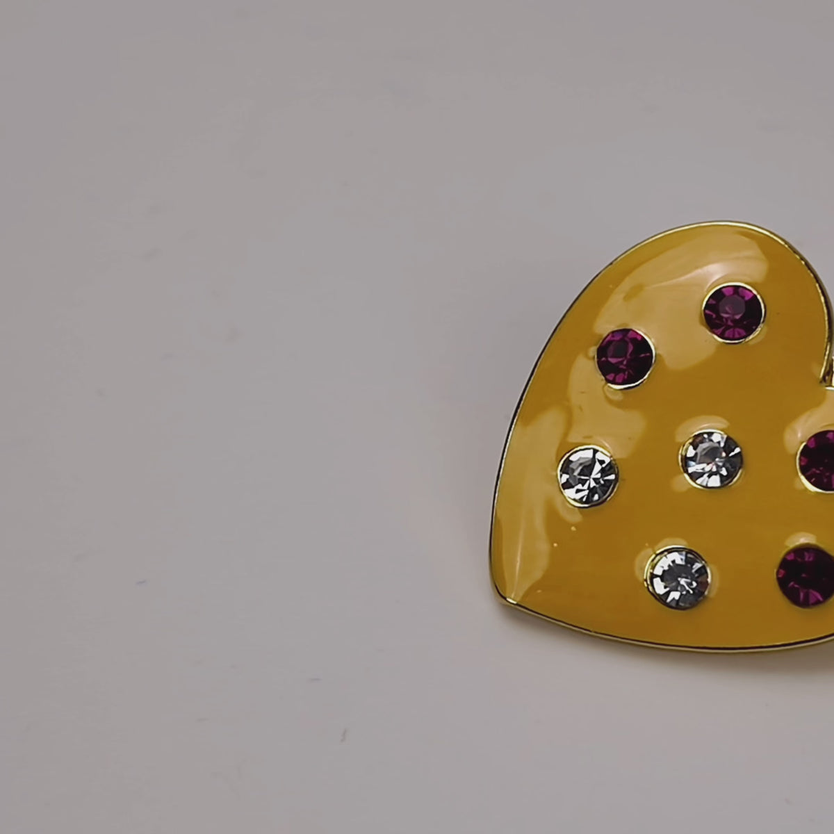  Colorful heart stud earrings featuring a yellow finish, red, blue and green crystals, and polished gold detailing.