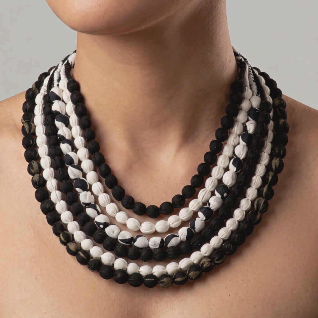 Close view of Kenza Cloth Bead Bib featuring mixed black and white textile covered beads. 