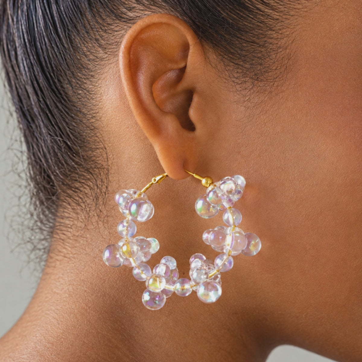 Close up of Alana Cloud Bubble Hoops showing translucent clustered bubbles with a rainbow reflective finish.