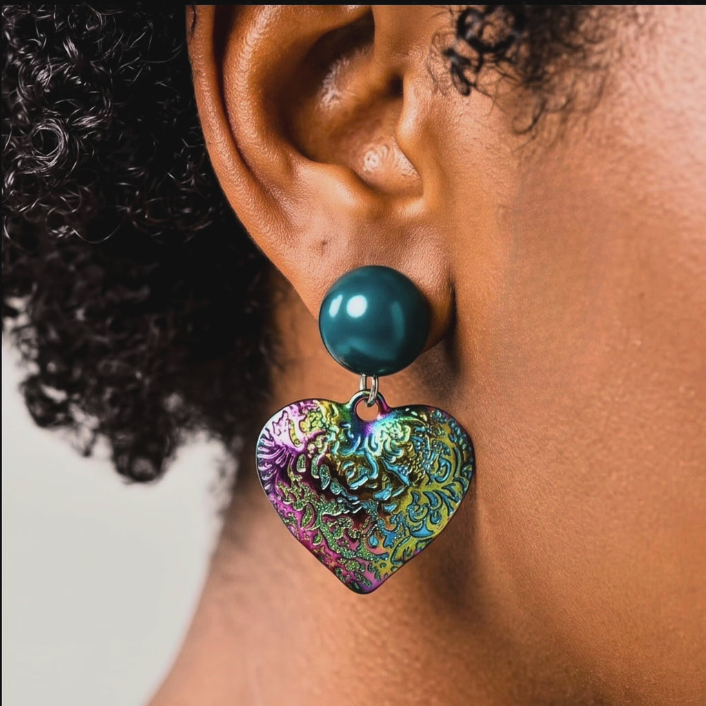 Colorful heart statement earrings with glossy teal glass pearl studs and textured iridescent rainbow drops.