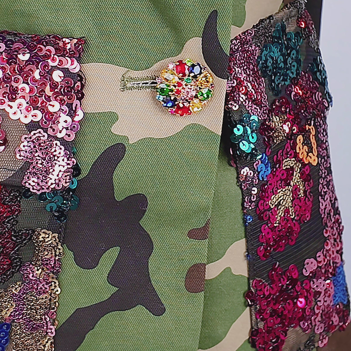 Women's hooded statement blazer featuring green camouflage, multicolor sequins and decorative jeweled cuff buttons.