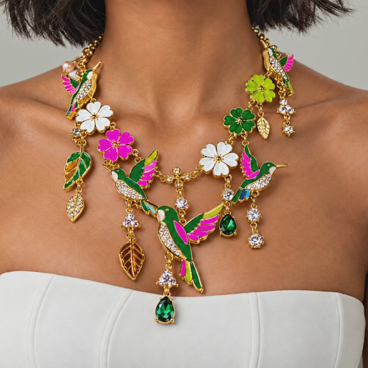 Close up of Cherish Hummingbird Necklace showcasing vibrant enamel wings, sparkling crystals and intricate floral detailing.