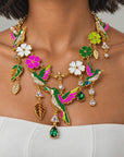 Close up of Cherish Hummingbird Necklace showcasing vibrant enamel wings, sparkling crystals and intricate floral detailing.