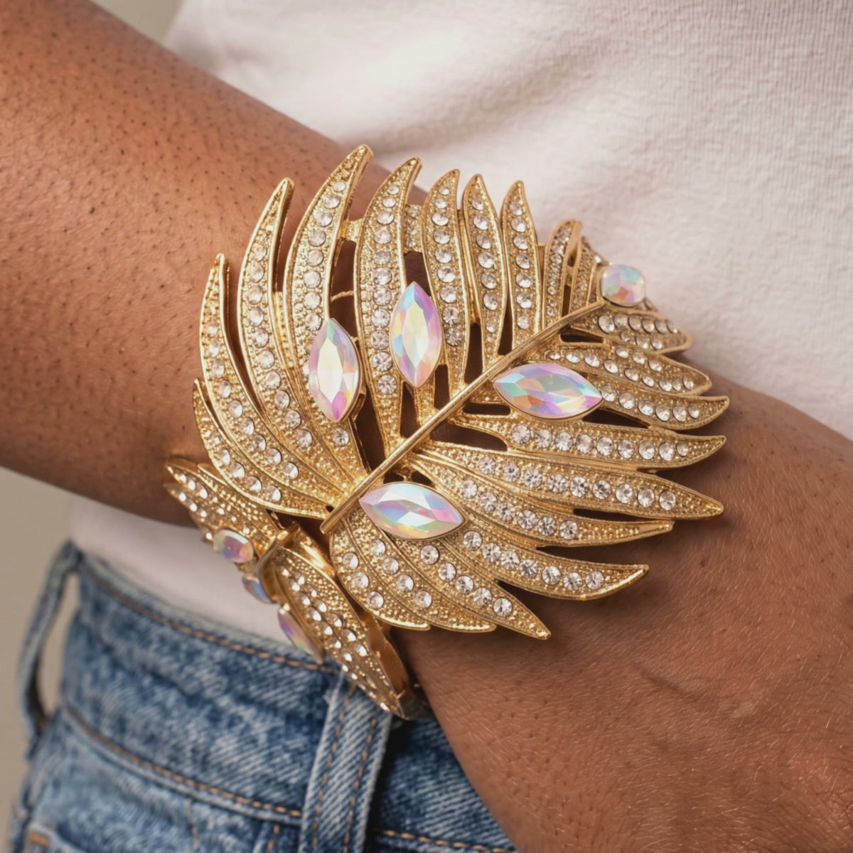 Sassy Jones Calypso Palm Cuff featuring layered gold leaves, clear crystals and rainbow iridescent marquise stones.