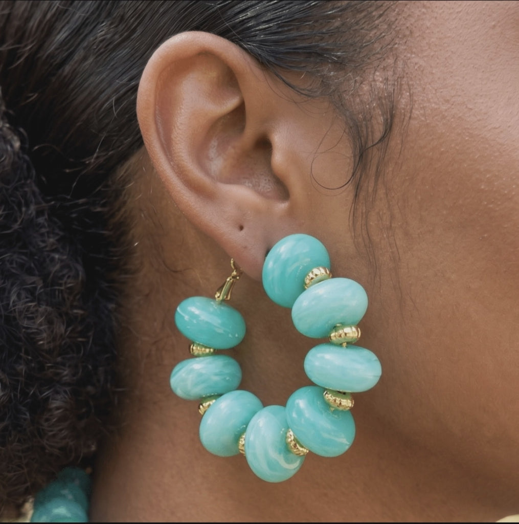Kamaria Coconut Shell Statement Hoops in Riviera Teal featuring oversized marbled teal coconut shell pieces and gold accents.