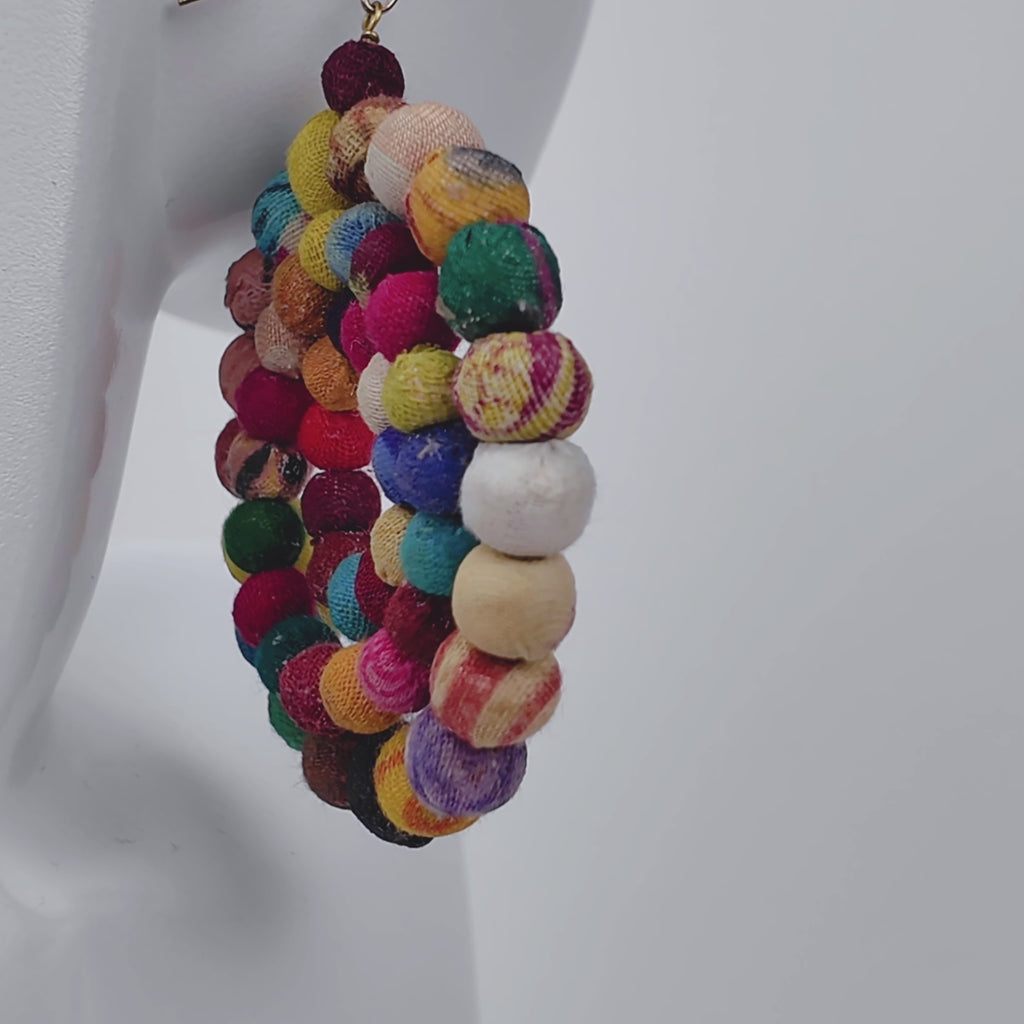Colorful fabric bead earrings with an open circular silhouette and gold colored hook ear wires.