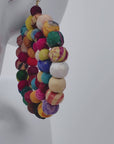 Colorful fabric bead earrings with an open circular silhouette and gold colored hook ear wires.