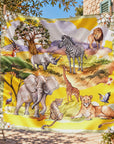 Yellow oversized square scarf featuring watercolor inspired African wildlife illustrations and botanical border detailing.