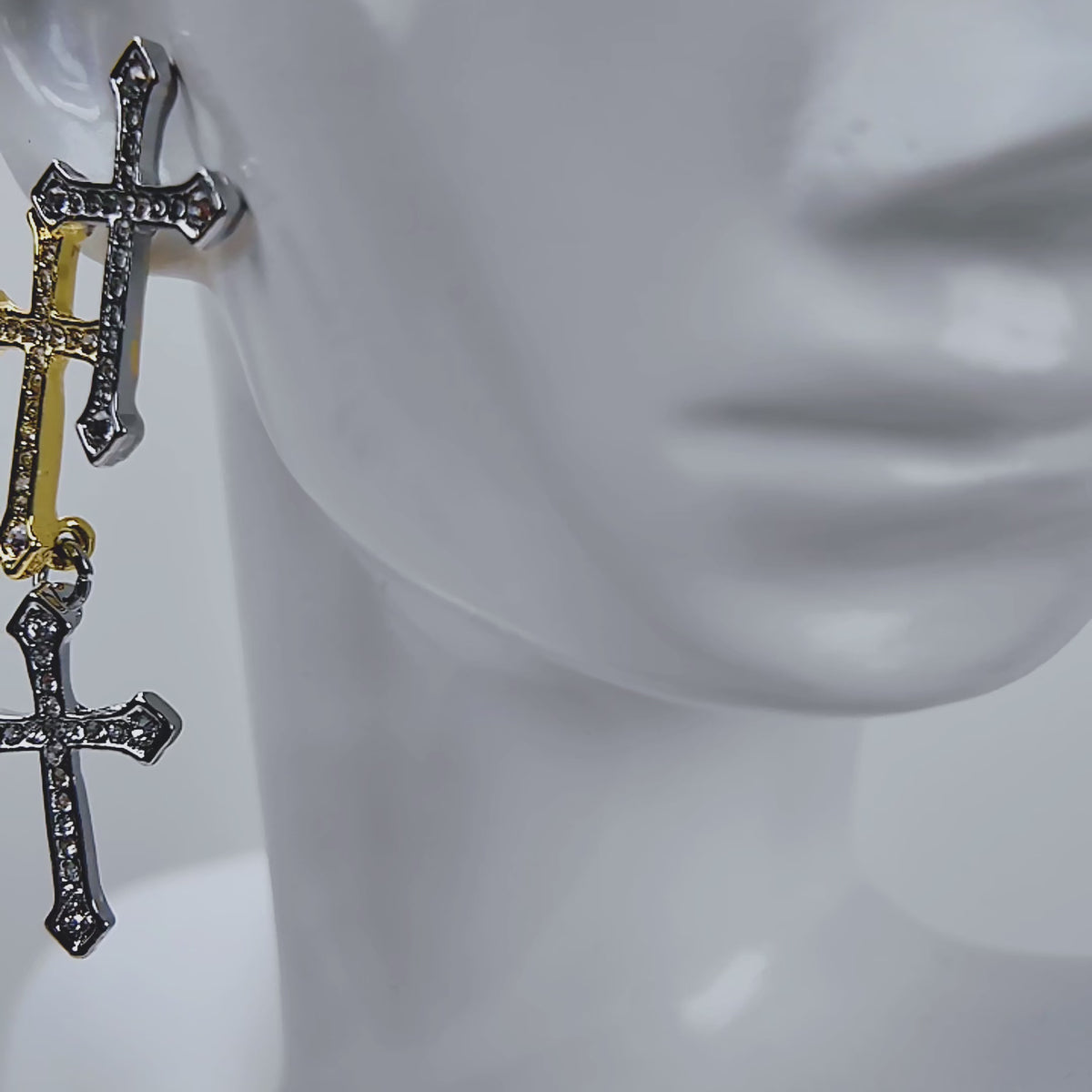 Trinity 18K Cross Sparkling Earrings featuring three cascading crystal crosses in gold and silver finishes.   Woman wearing Trinity statement earrings with layered gold and silver crystal cross motifs.   Sassy Jones Trinity drop earrings featuring three sparkling crosses in contrasting mixed metal finishes.   Close up of crystal cross earrings with a silver cross stud, gold center cross and dangling silver cross.   Trinity faith inspired earrings featuring cascading crystal embellished crosses in gold and s