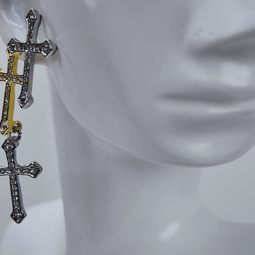 Trinity 18K Cross Sparkling Earrings featuring three cascading crystal crosses in gold and silver finishes.   Woman wearing Trinity statement earrings with layered gold and silver crystal cross motifs.   Sassy Jones Trinity drop earrings featuring three sparkling crosses in contrasting mixed metal finishes.   Close up of crystal cross earrings with a silver cross stud, gold center cross and dangling silver cross.   Trinity faith inspired earrings featuring cascading crystal embellished crosses in gold and s
