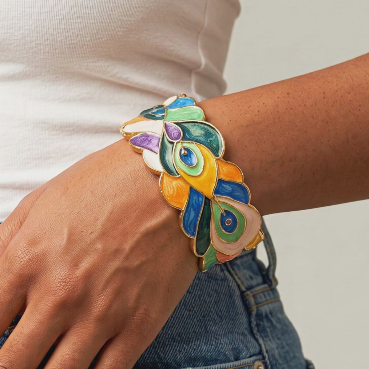 Sculptural peacock inspired cuff bracelet with colorful hand painted enamel style detailing and Gold tone finish.