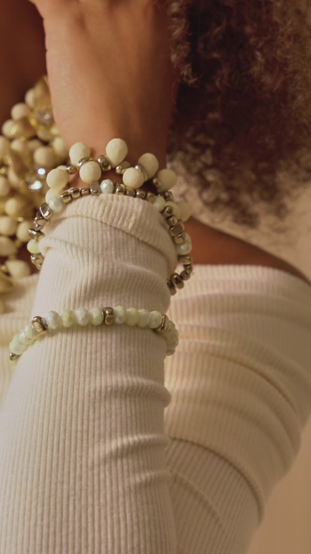 Stacked ivory and gold stretch bracelets with creamy beads and metallic accents in a soft honey toned design.