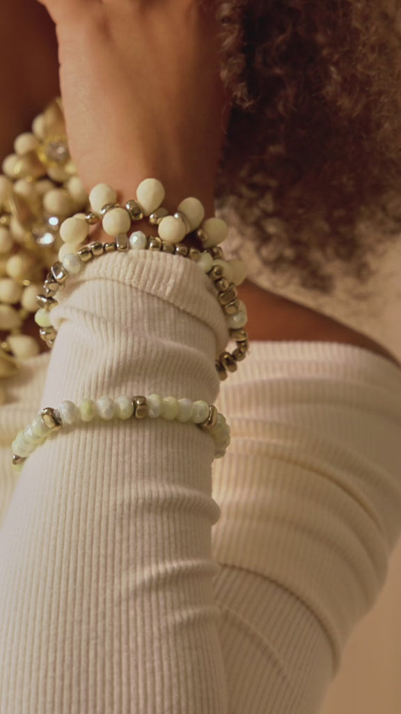 Stacked ivory and gold stretch bracelets with creamy beads and metallic accents in a soft honey toned design.